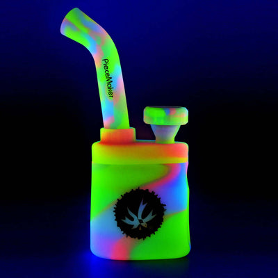 Piecemaker Klutch 7" Silicone Water Pipe in neon colors with Hex TEK downstem and stainless steel bowl under UV light.